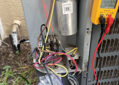 Technician testing the capacitor and contactor in an outdoor AC unit with a multimeter in Lake Worth