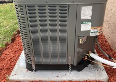 New outdoor AC condenser on a fresh pad in a mulched side yard in Delray Beach