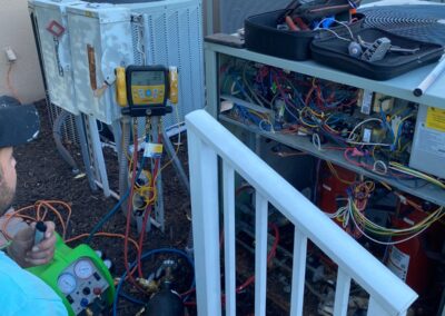 Technician with gauges at a bank of commercial condensers beside an HOA clubhouse in Boynton Beach