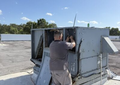 Technician working on a rooftop package air conditioning unit on an office roof in Boca Raton