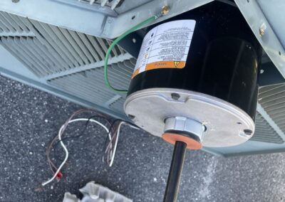 New condenser fan motor on top of an outdoor AC unit next to the old part in West Palm Beach