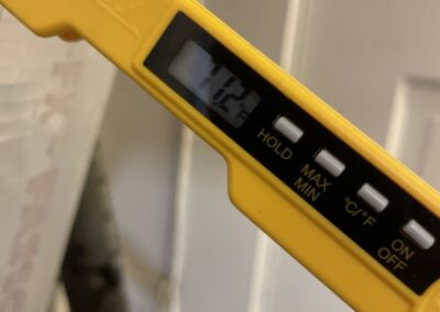 Digital thermometer reading supply air temperature at a vent after an AC repair in West Palm Beach